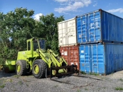 Four storage containers next to a forklift