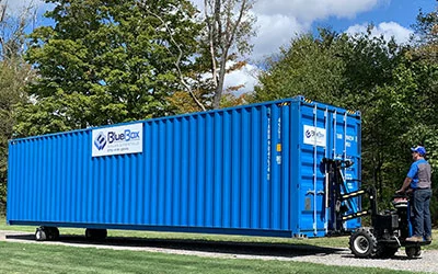 A blue storage container being driven on stone using a mule device in Lycoming County, PA