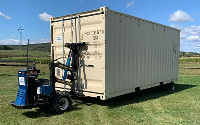 A plain colored storage container being driven on grass using a mule device in Tioga County, PA